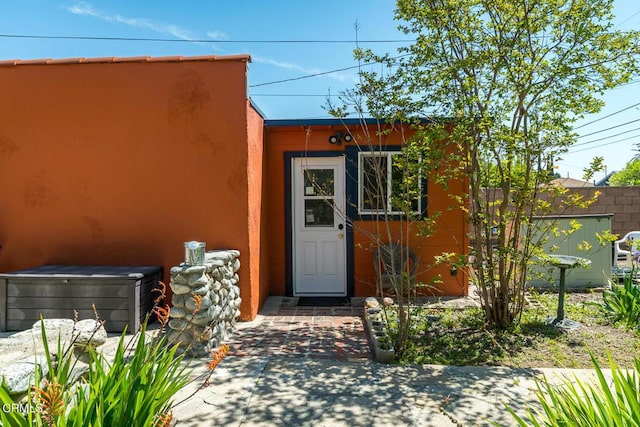 doorway to property featuring fence and stucco siding
