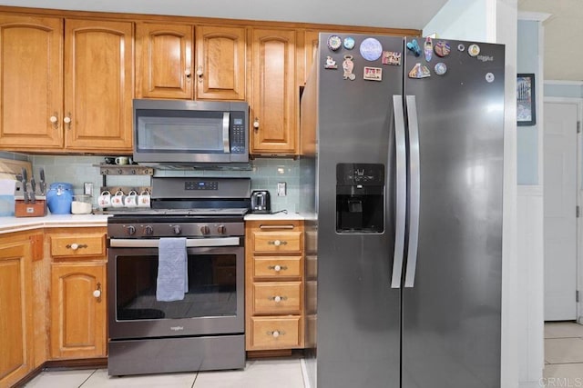 kitchen featuring stainless steel appliances, light tile patterned flooring, light countertops, and decorative backsplash