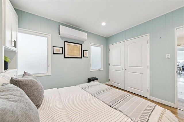 67 Corona Ave, Long Beach, CA 90803 - bedroom featuring a wall unit AC, a decorative wall, a closet, baseboards, and wood finished floors