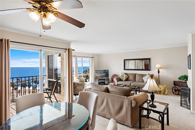 carpeted living area with a water view, ornamental molding, baseboards, and ceiling fan