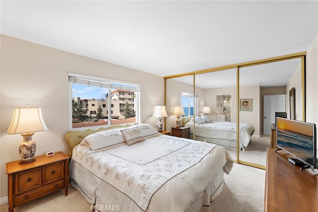 bedroom featuring baseboards, light colored carpet, and a closet