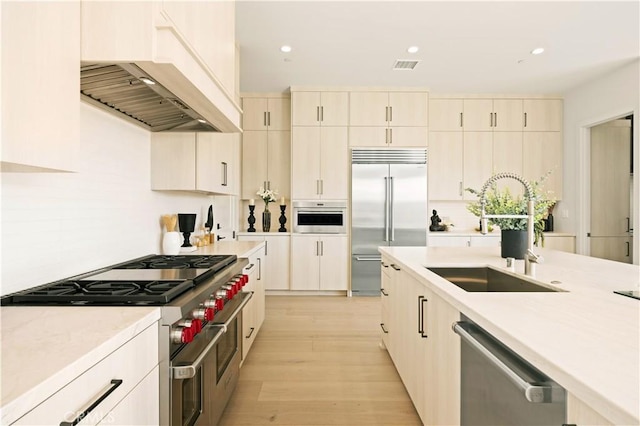 128 Mossvine, Irvine, CA 92618 - kitchen with visible vents, high end appliances, custom range hood, a sink, and light wood-style flooring