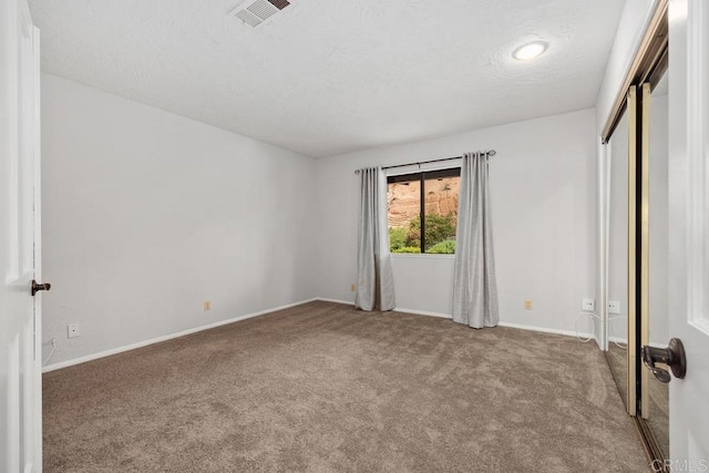 unfurnished bedroom with carpet floors, visible vents, a closet, baseboards, and a textured ceiling