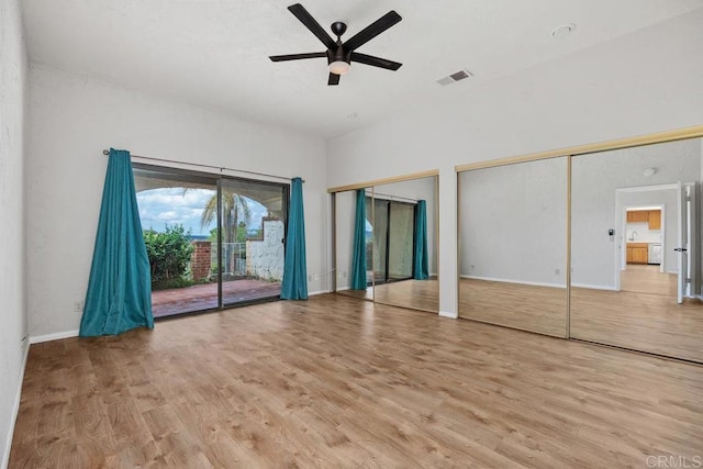 unfurnished bedroom with access to exterior, visible vents, wood finished floors, baseboards, and two closets
