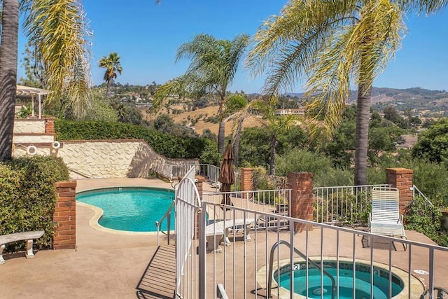 community pool featuring a hot tub, fence, and a patio area