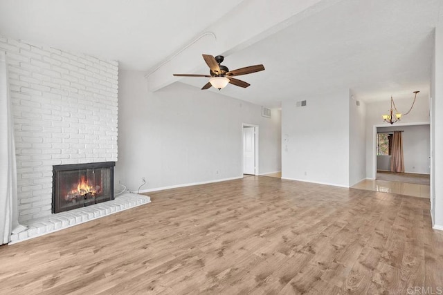 unfurnished living room featuring ceiling fan with notable chandelier, vaulted ceiling with beams, a brick fireplace, and wood finished floors