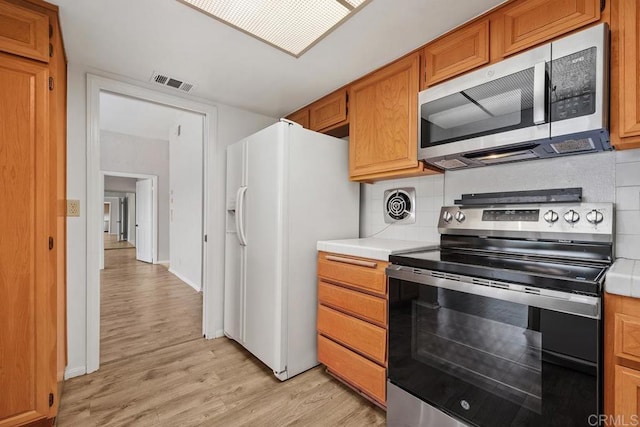 kitchen with light countertops, stainless steel appliances, visible vents, and light wood-type flooring