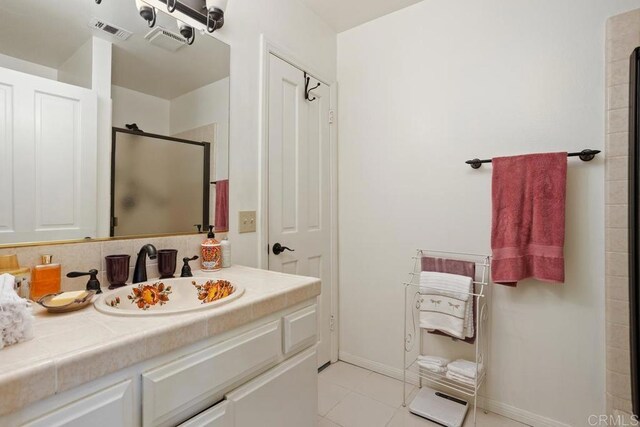 bathroom with tile patterned flooring, vanity, baseboards, a shower stall, and visible vents