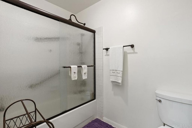 bathroom with toilet and shower / bath combination with glass door