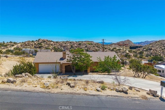 view of front of property with a chimney, a mountain view, stucco siding, and an attached garage