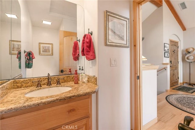 bathroom featuring visible vents, lofted ceiling with beams, wood finished floors, and vanity
