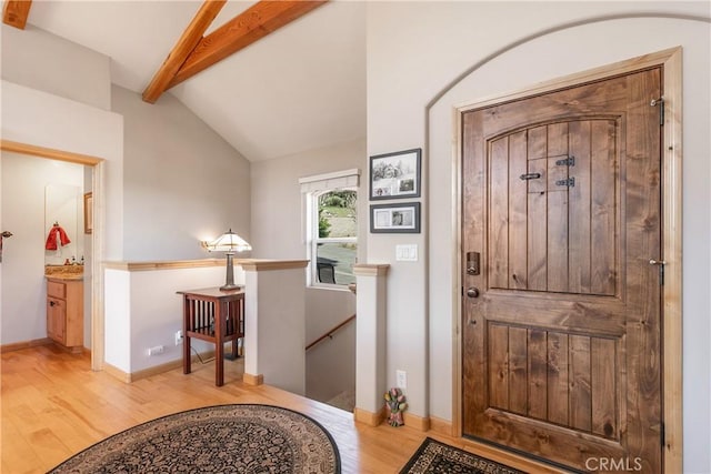 entrance foyer featuring light wood finished floors, vaulted ceiling with beams, and baseboards