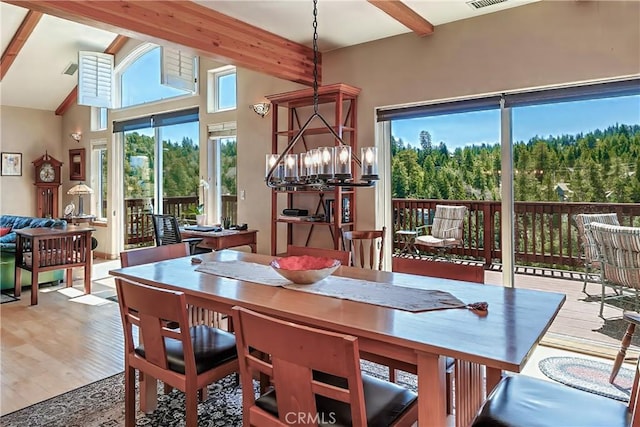 dining space featuring beamed ceiling, an inviting chandelier, wood finished floors, and visible vents