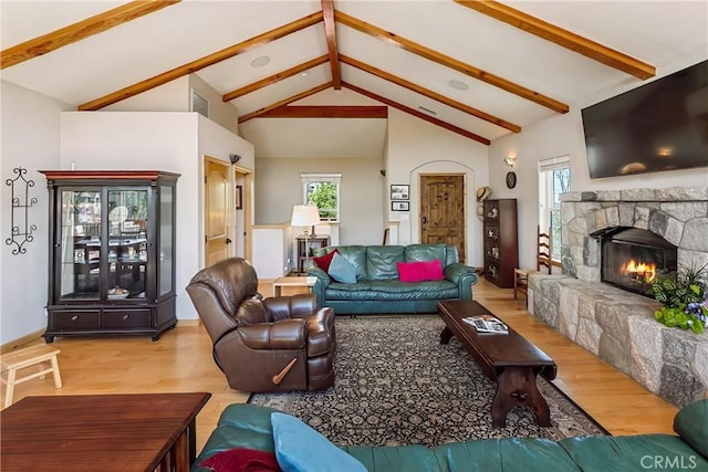 living room with a stone fireplace, a wealth of natural light, wood finished floors, and visible vents