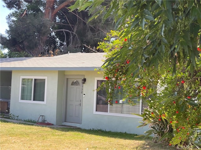 doorway to property featuring stucco siding and a yard
