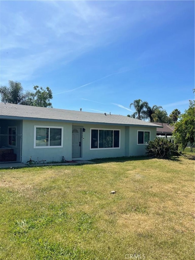 single story home with stucco siding and a front yard