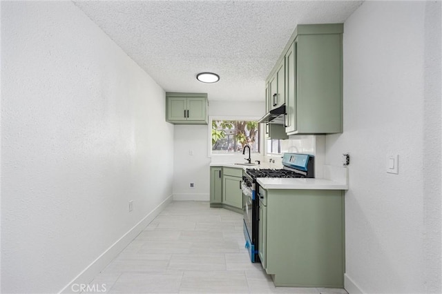 kitchen featuring green cabinetry, light countertops, baseboards, under cabinet range hood, and stainless steel gas range oven