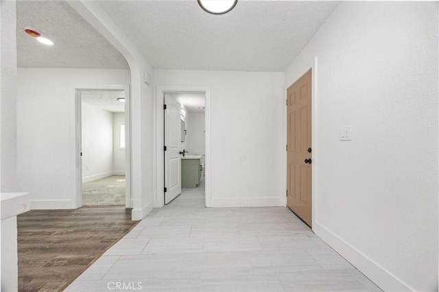 hallway featuring a textured ceiling and baseboards