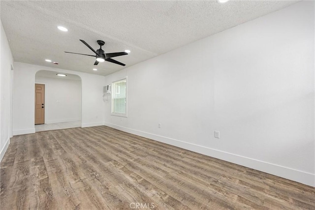 spare room featuring recessed lighting, arched walkways, wood finished floors, ceiling fan, and a textured ceiling