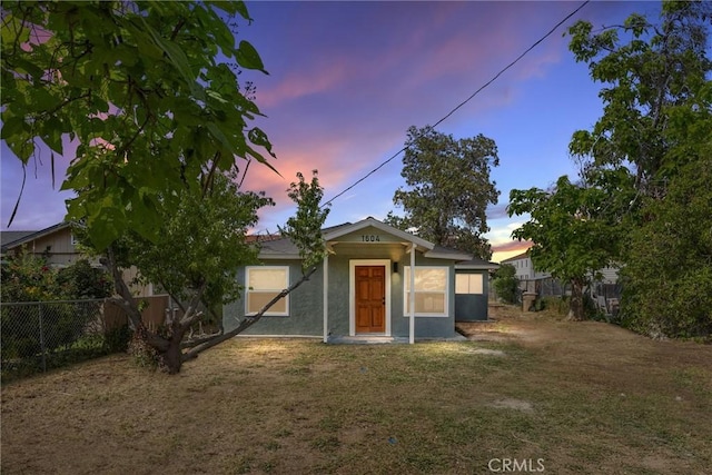 view of front of house with a front yard, stucco siding, and fence
