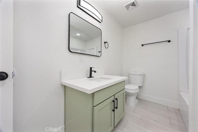 bathroom with vanity, a tub, toilet, visible vents, and baseboards