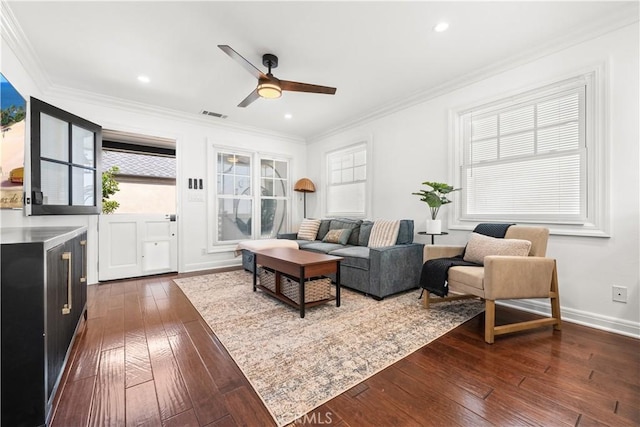 living room with baseboards, ceiling fan, dark wood-style floors, visible vents, and crown molding