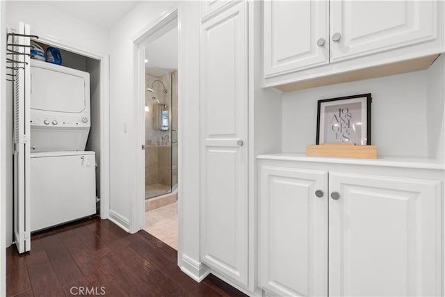washroom with stacked washer and clothes dryer and dark wood finished floors