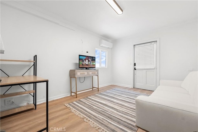 living room with wood finished floors, a wall unit AC, and baseboards