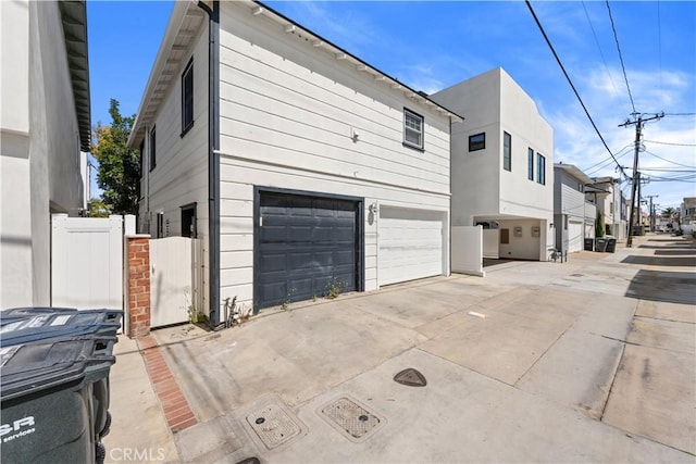 view of side of home with a garage, a gate, a residential view, and concrete driveway
