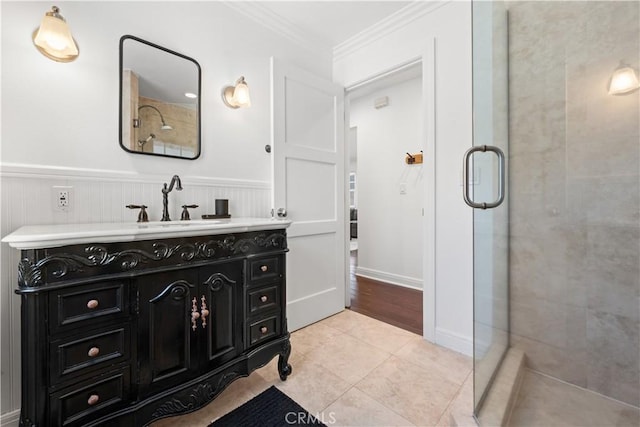 bathroom with tiled shower, tile patterned flooring, ornamental molding, a wainscoted wall, and vanity