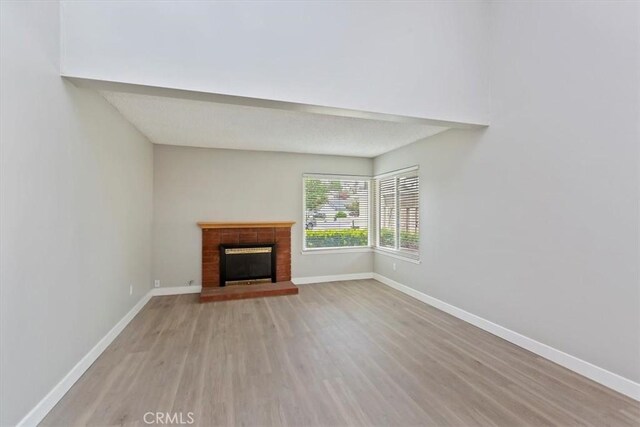 810 Hacienda Dr, Riverside, CA 92507 - unfurnished living room with baseboards, light wood-style flooring, and a brick fireplace