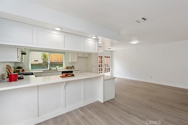 810 Hacienda Dr, Riverside, CA 92507 - kitchen with visible vents, light countertops, light wood finished floors, french doors, and a peninsula