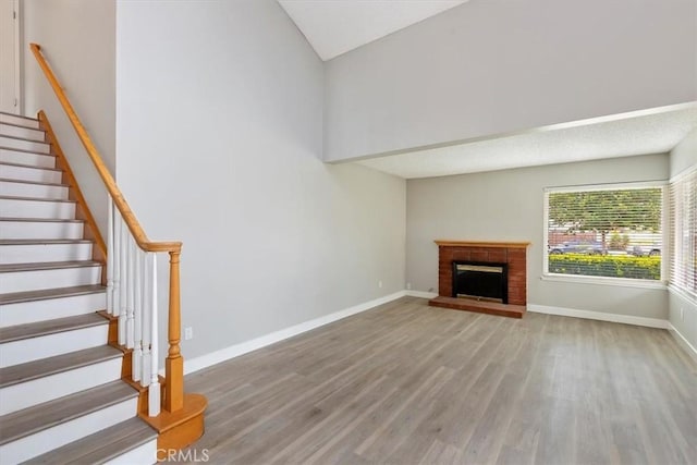 810 Hacienda Dr, Riverside, CA 92507 - unfurnished living room featuring stairs, vaulted ceiling, a fireplace, light wood finished floors, and baseboards