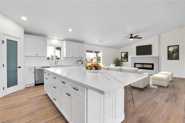 kitchen featuring light wood finished floors, a center island, a ceiling fan, dishwasher, and white cabinets