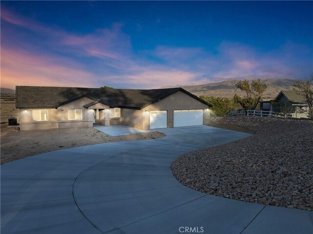 single story home with stucco siding, a mountain view, driveway, an attached garage, and fence