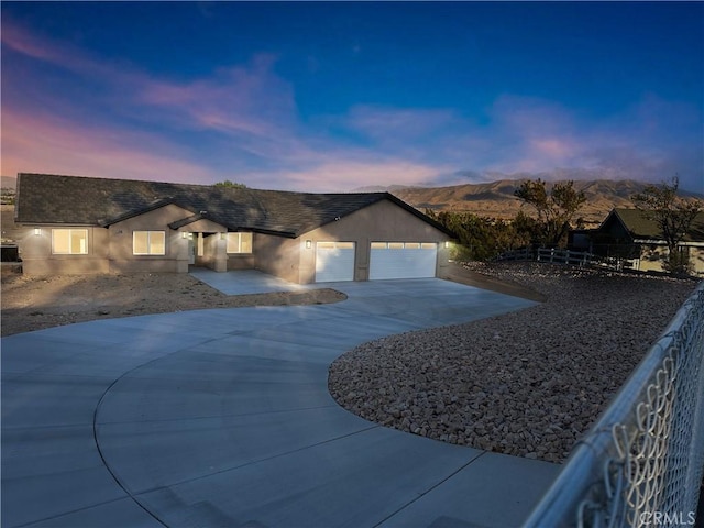 ranch-style house featuring concrete driveway, a garage, stucco siding, and a mountain view