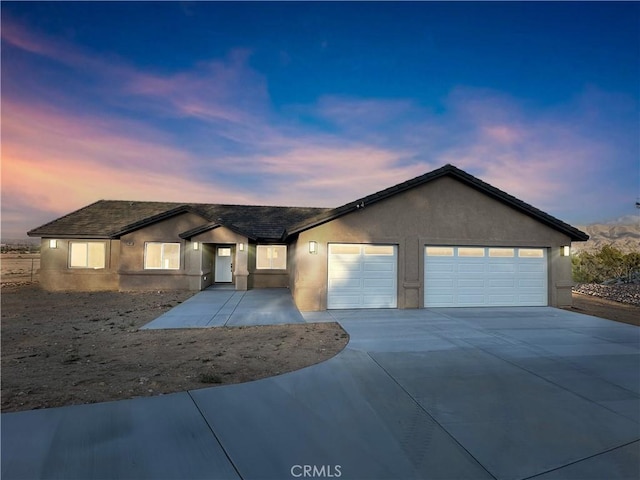 single story home featuring driveway, stucco siding, and a garage