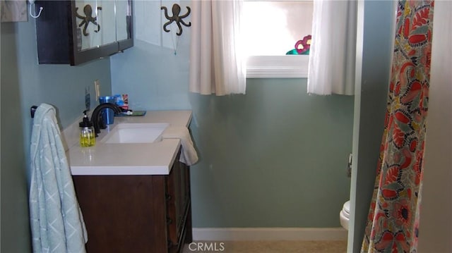 bathroom with baseboards, toilet, and vanity