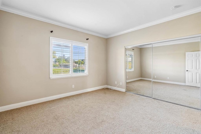 unfurnished bedroom with crown molding, carpet floors, baseboards, and a closet