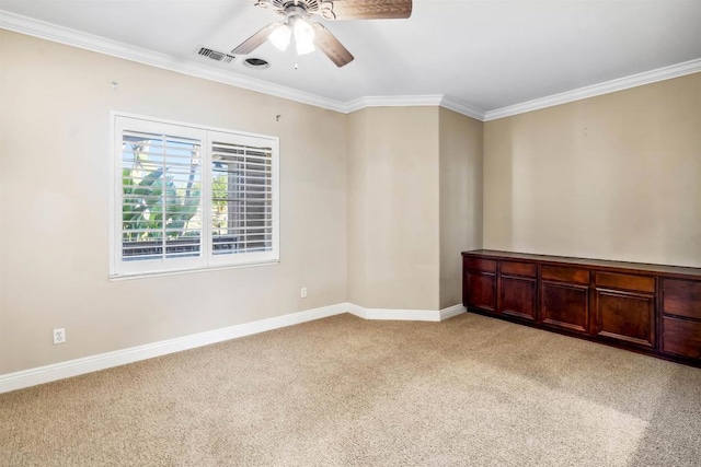 spare room with crown molding, a ceiling fan, visible vents, and light carpet