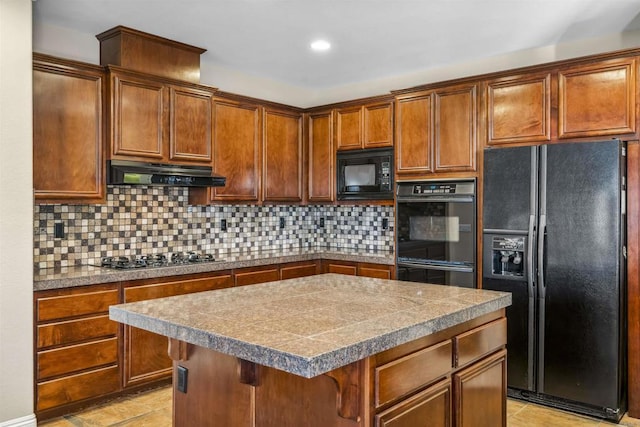 kitchen with a kitchen island, tasteful backsplash, black appliances, tile counters, and under cabinet range hood