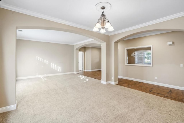 spare room with ornamental molding, baseboards, arched walkways, carpet, and a notable chandelier