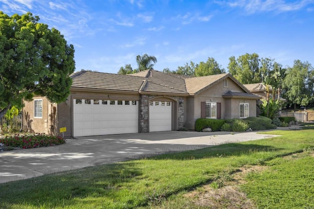 ranch-style house featuring a tiled roof, a front yard, a garage, concrete driveway, and stucco siding