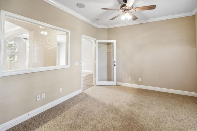 carpeted spare room with crown molding, baseboards, ceiling fan, and french doors