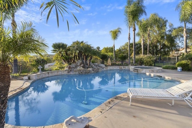view of swimming pool with a patio, fence, and a pool with connected hot tub