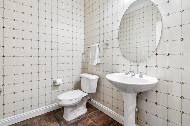 half bathroom with a sink, toilet, and tile walls