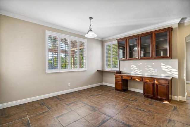 unfurnished dining area featuring built in study area, baseboards, ornamental molding, and stone finish flooring