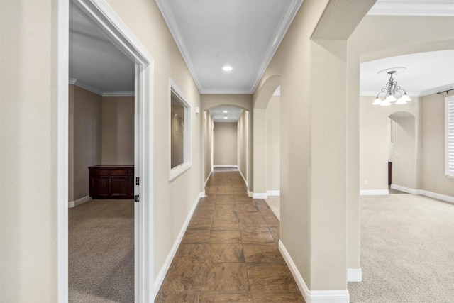hall with crown molding, arched walkways, baseboards, and carpet floors