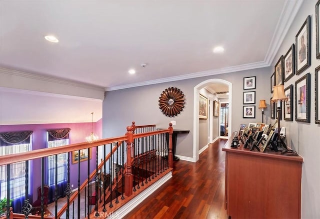 hallway featuring arched walkways, dark wood finished floors, recessed lighting, and an upstairs landing