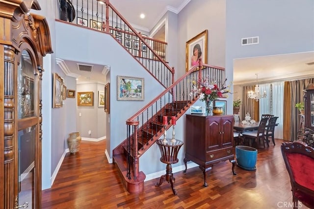stairs with crown molding, visible vents, and a towering ceiling